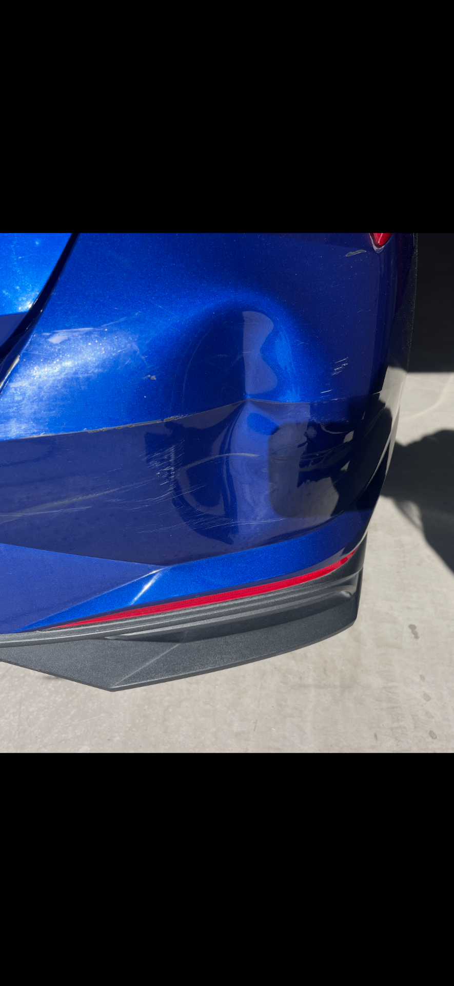 Blue sedan rear bumper with deep scuffs and scratches before respray
