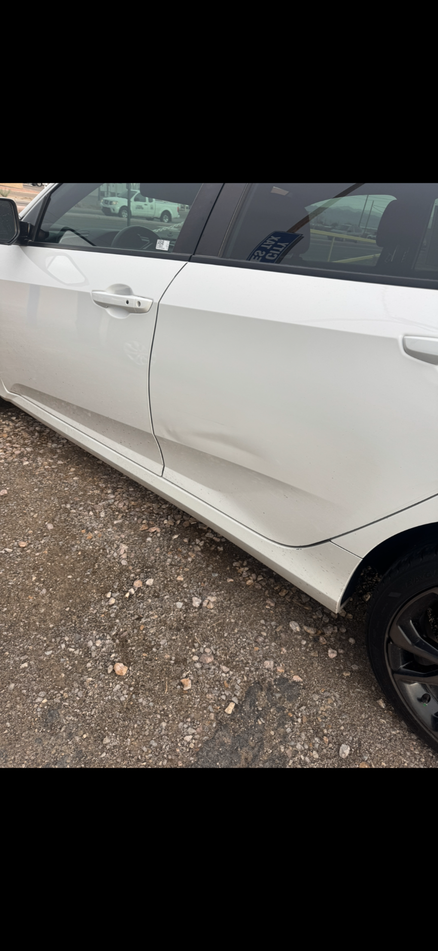 White Honda Civic rear door with large dent before repair