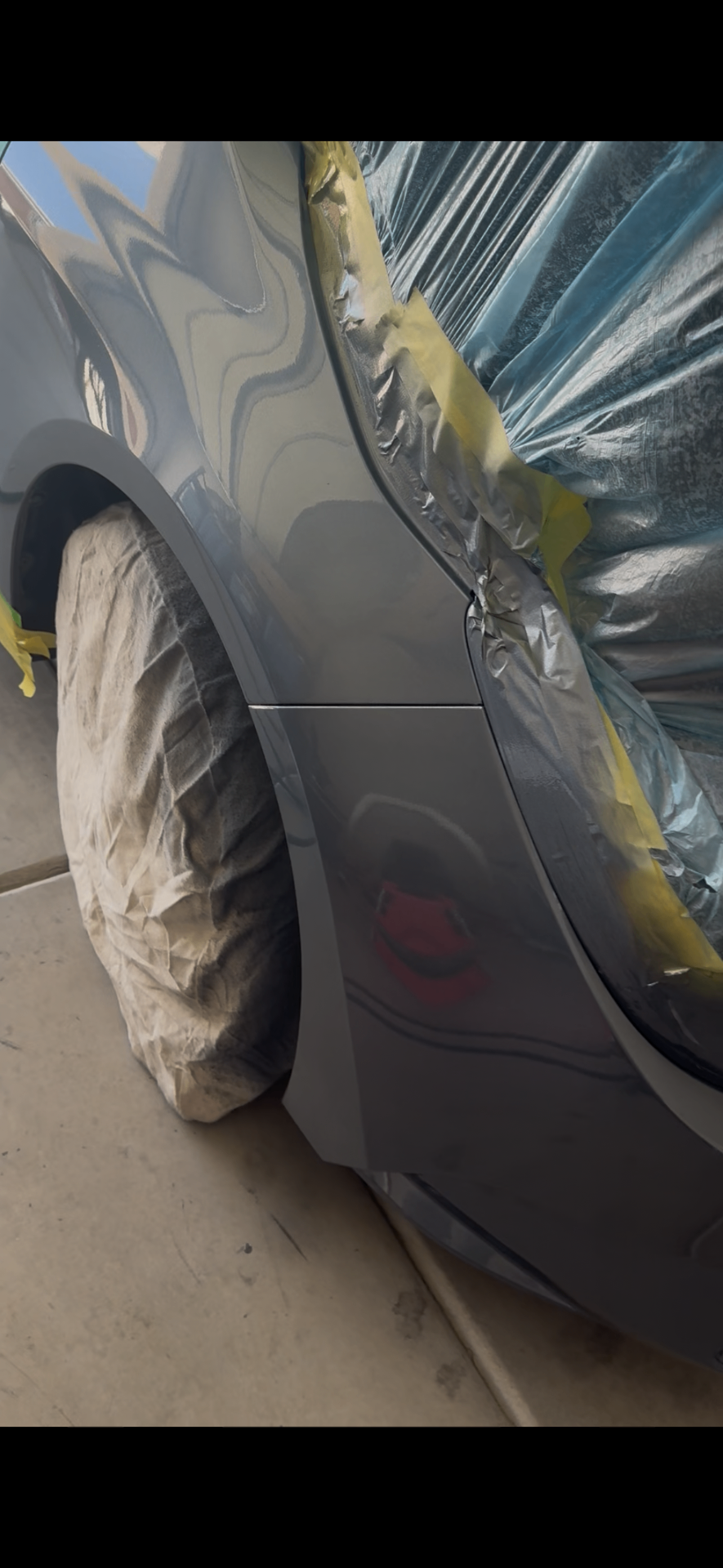 Gray sedan front fender masked off mid-respray after body work